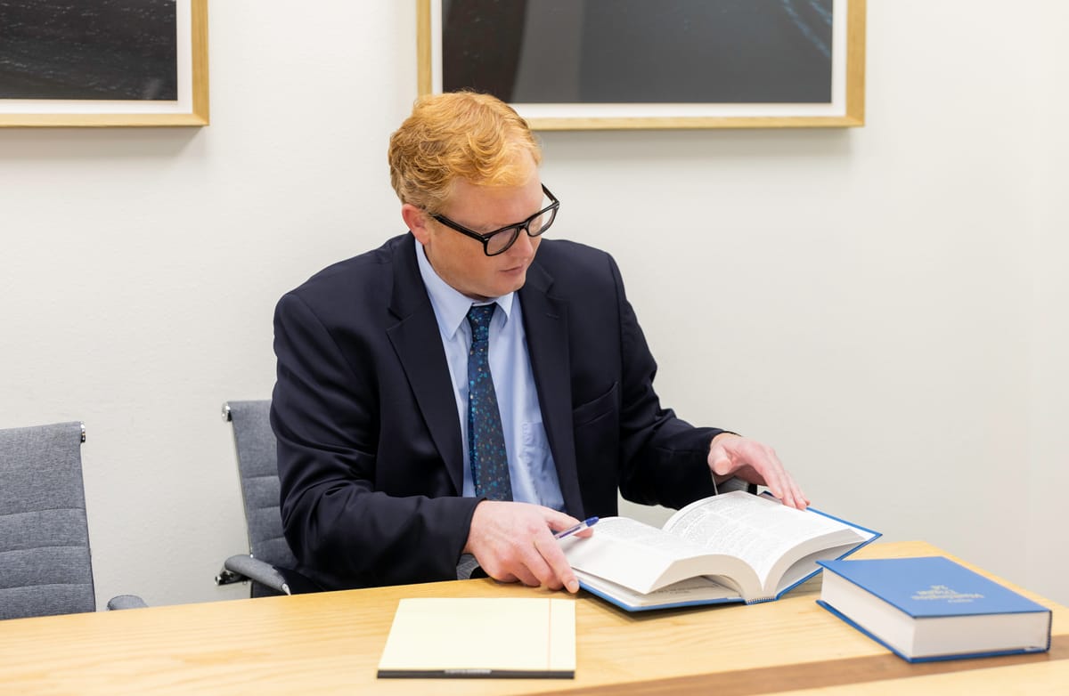 Attorney John Brennan reading a law book at the Kitsap Law Group conference table