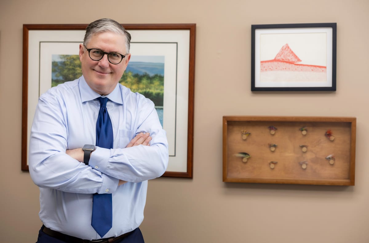 David A. Weibel, Partner at Kitsap Law Group, in his office with arms crossed beside framed art